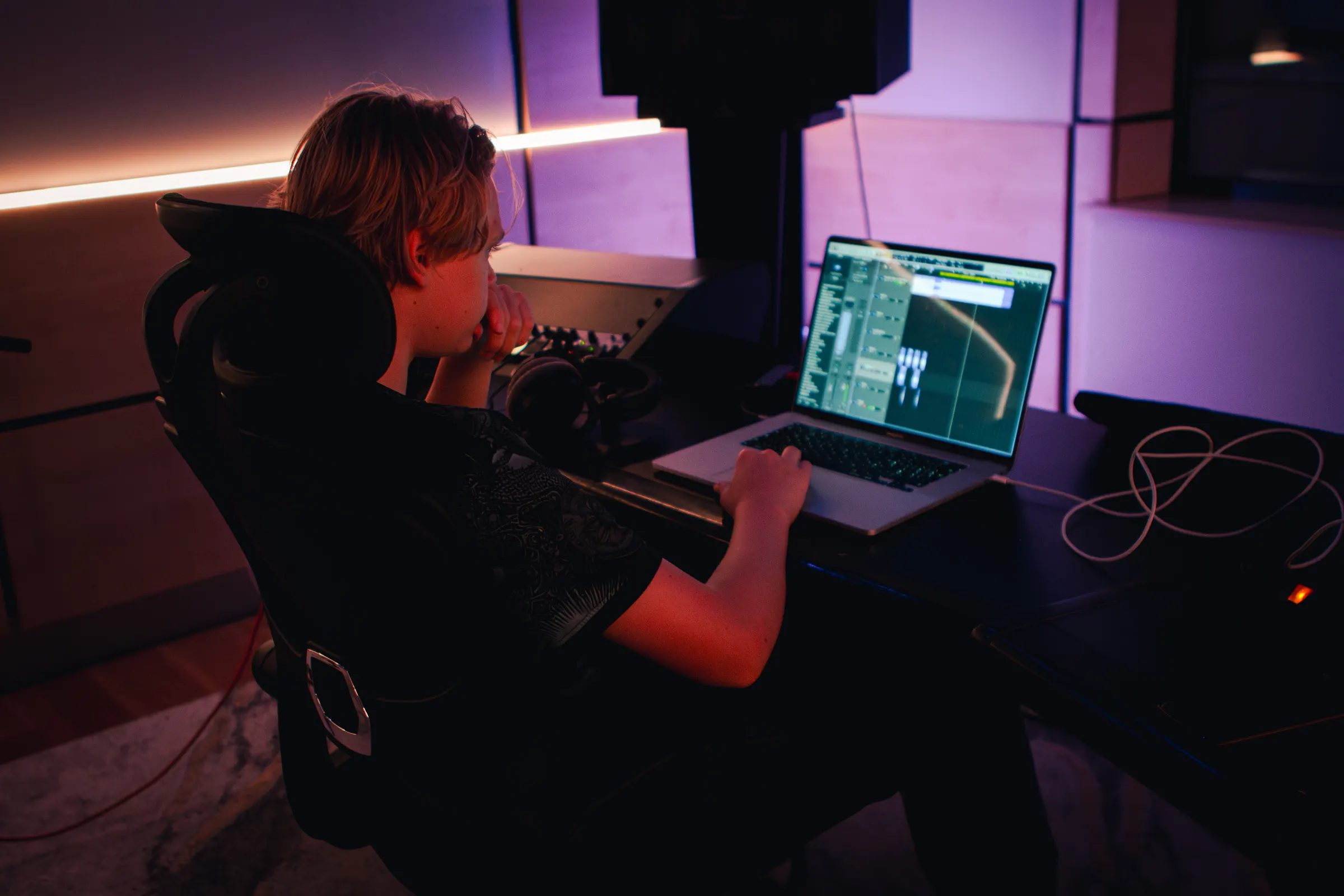 Handen op een laptop met muzieksoftware en plug-ins op het scherm