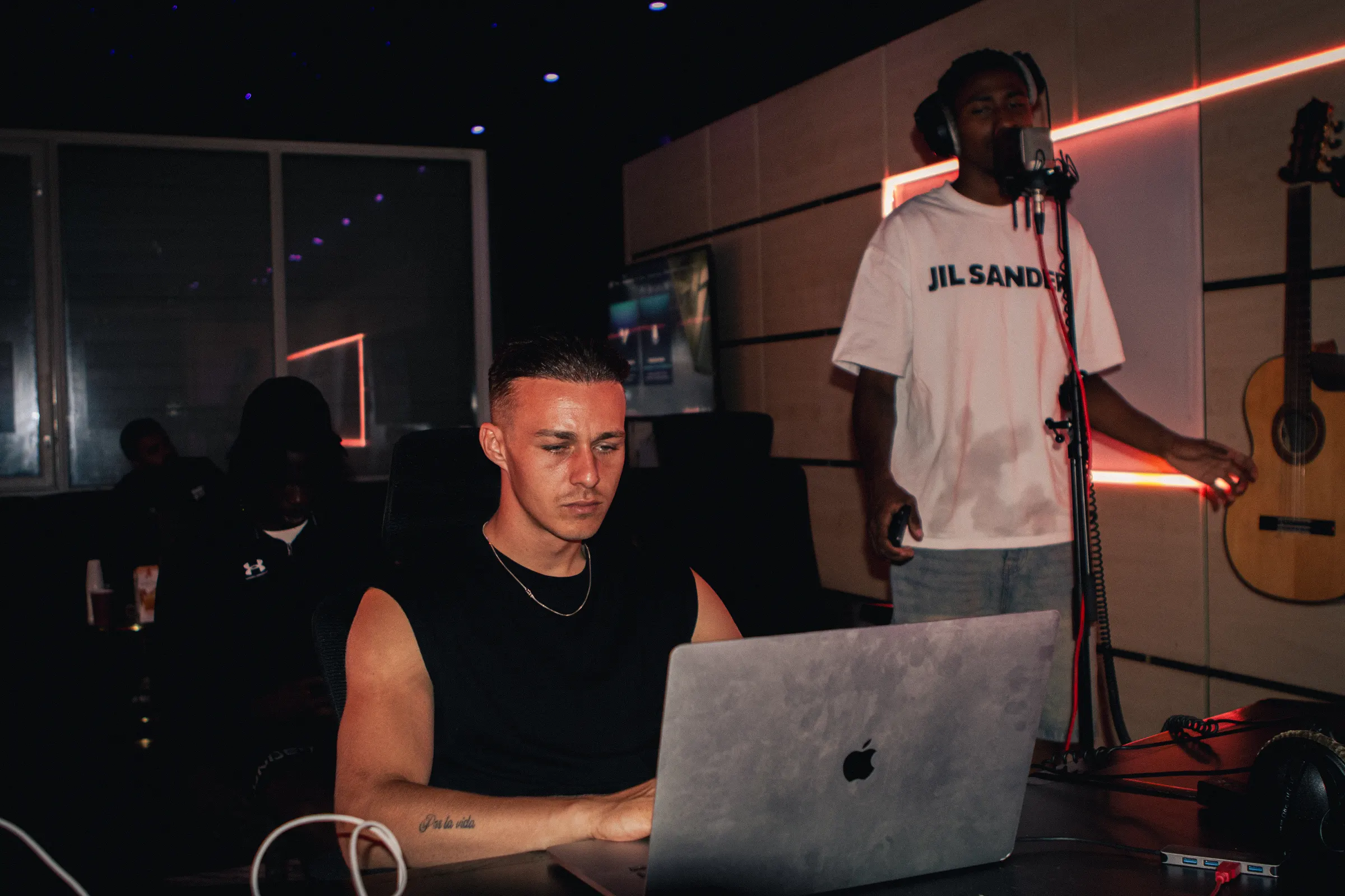 Een producer aan de laptop terwijl een zanger opneemt